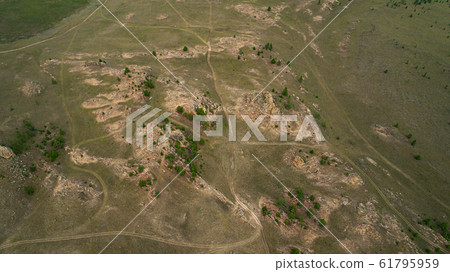 Baikal region. Dirt road on Tazheranskaya steppe near the stone rocks, called the Valley of the Stone Spirits. Aerial 61795959
