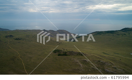 Baikal region. Dirt road on Tazheranskaya steppe near the stone rocks, called the Valley of the Stone Spirits. Aerial 61795994