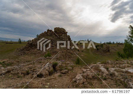 Baikal region. Dirt road on Tazheranskaya steppe near the stone rocks, called the Valley of the Stone Spirits. 61796197