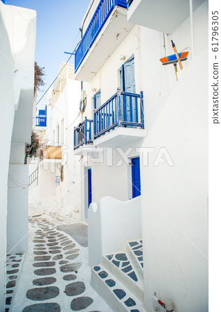 The narrow streets of the island with blue balconies, stairs and flowers in Greece. The narrow streets of the island with blue balconies, stairs and flowers in Greece. 61796305