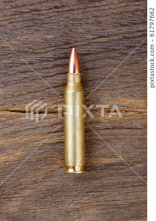 Close-up of rifle bulet on old wood desk background. 61797662