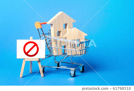 Houses in a shopping cart and easel red prohibition sign NO. Inaccessibility, lack housing, deficit. Seizure, freezing of assets by a bank, court. Expensive maintenance, impossibility of restoration 61798518