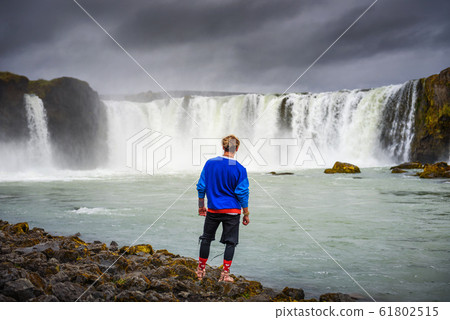 Hiker standing at the Godafoss waterfall in Iceland 61802515