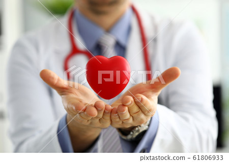 Male medicine doctor hands holding and covering red toy heart 61806933