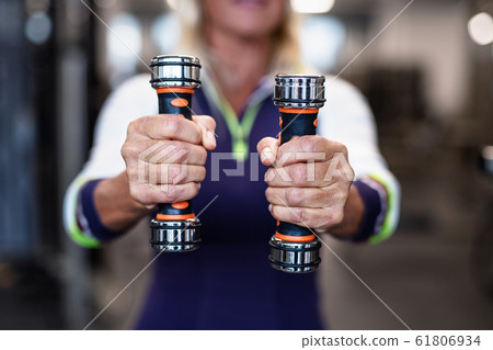 A midsection of senior woman with dumbbells in gym, doing exercise. A midsection of senior woman with dumbbells in gym, doing exercise. 61806934