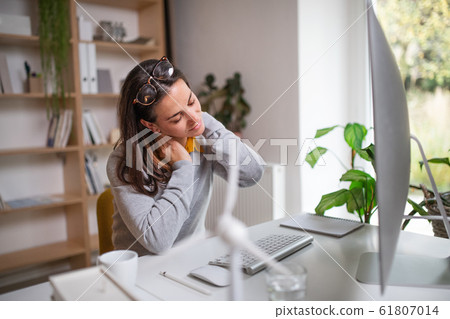 Businesswoman at the desk indoors in office, feeling pain in neck. Businesswoman at the desk indoors in office, feeling pain in neck. 61807014