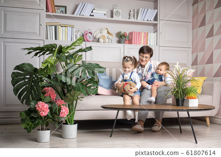 Grandmother sits with granddaughters in the living room. 61807614