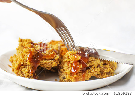 Forks and knives are shearing crispy chicken fried breast. 61809188