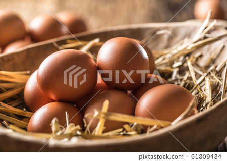 Fresh raw eggs in straw and wooden bowl on rustic Fresh raw eggs in straw and wooden bowl on rustic 61809484