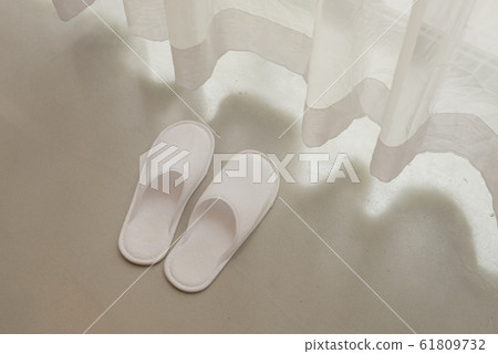 White slippers by white sheer curtains and soft sunlight, vacation concept 61809732