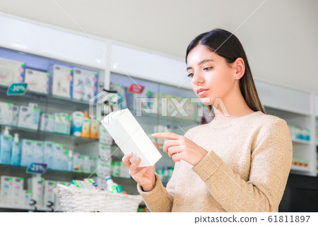 read drug instruction. woman reading instruction or label of the product in pharmacy or store 61811897