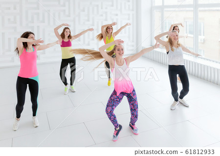 Young women in sportswear dancing with hands raised up at dance fitness class Young women in sportswear dancing with hands raised up at dance fitness class 61812933