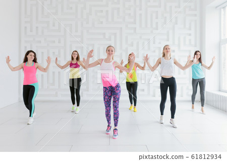 Young women in colorful sportswear at dance fitness class in white fitness studio 61812934