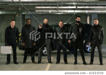 Row of intercultural armed gangsters or criminals in black jackets and jeans 61813550