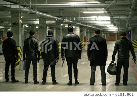 Rear view of row of criminals or gangsters in black standing on parking area 61813901
