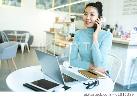 Pretty young smiling businesswoman or student talking by smartphone in cafe 61815359