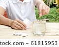 woman dropping effervescent tablet in glass of water 61815953