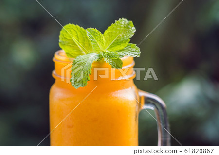 Mango smoothie in a glass Mason jar and mango on a green background. Mango shake. Tropical fruit concept 61820867