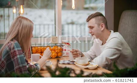 A young man and woman having a breakfast in cafe - christmas time 61821741