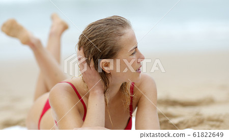 Sexy woman in a bikini relaxes on a sandy beach at the ocean 61822649