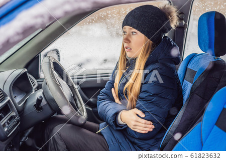 Woman in a car during a snowfall, problems on the road Woman in a car during a snowfall, problems on the road 61823632