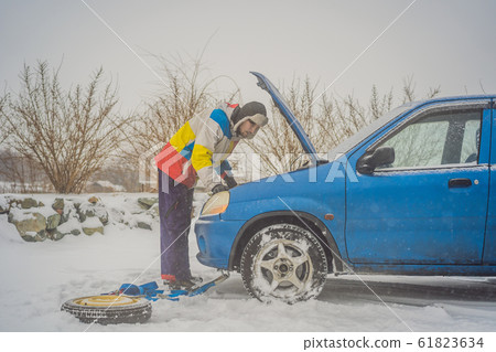 upset young men looking under the hood broken car on winter road 61823634