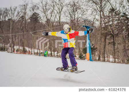 Young man jumping with a snowboard in the mountains 61824376