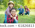 Happy asian siblings smiling with their father and mother sitting in background. 61826813