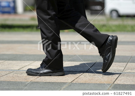 Foot of man walking with leather shoes and suit in front of station in the morning 61827491