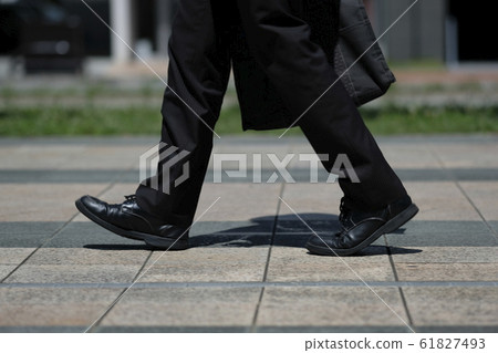 Foot of man walking with leather shoes and suit in front of station in the morning Foot of man walking with leather shoes and suit in front of station in the morning 61827493
