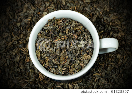 Dried leaves of green gunpowder tea in a white cup 61828897