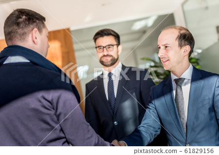 Group of confident business people greeting with a handshake at business meeting in modern office or closing the deal agreement by shaking hands. 61829156
