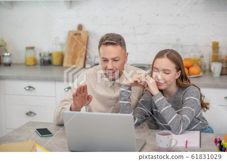 Long-haired girl in grey shirt and her father having a video call 61831029