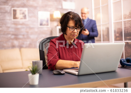 Old woman in her 60s using a modern laptop in her cozy house 61833236