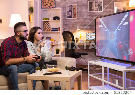 Boyfriend playing video games on television using controller Boyfriend playing video games on television using controller 61833264