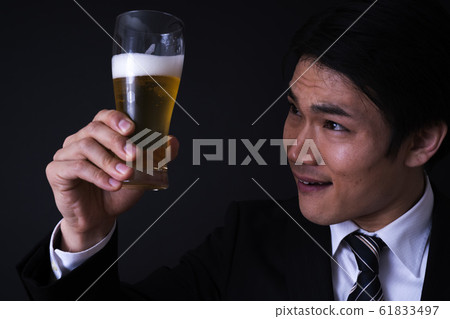 年輕的商人喝啤酒（黑背，西裝，領帶） 61833497