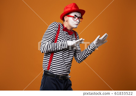Sad mime in red hat and vest on orange background Sad mime in red hat and vest on orange background 61833522