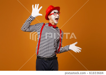 Smiling mime man in red hat, white gloves and striped t-shirt on blank orange background 61833684