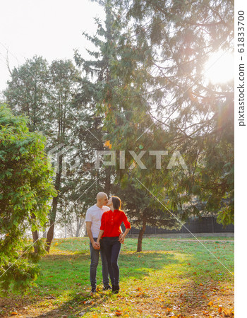 Happy lovers in the park at thuja in autumn sunny 61833700