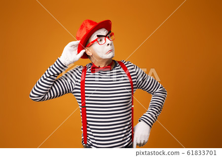 Listening mime red hat and striped t-shirt on blank orange background 61833701