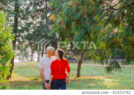 Happy lovers in the park at thuja in autumn sunny Happy lovers in the park at thuja in autumn sunny 61833742