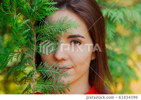 Beautiful woman in a green tree arborvitae. Beautiful woman in a green tree arborvitae. 61834399