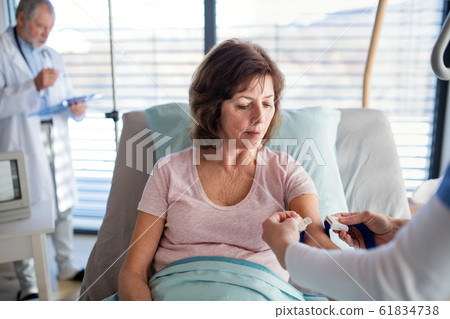 Doctor and nurse examining a senior woman patient in hospital. Doctor and nurse examining a senior woman patient in hospital. 61834738