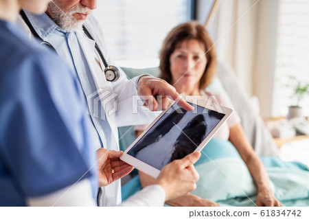 Senior male doctor examining a woman patient in hospital, checking X-ray. 61834742