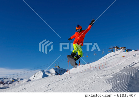 Snowboarder jumps from a springboard in a snowpark 61835407