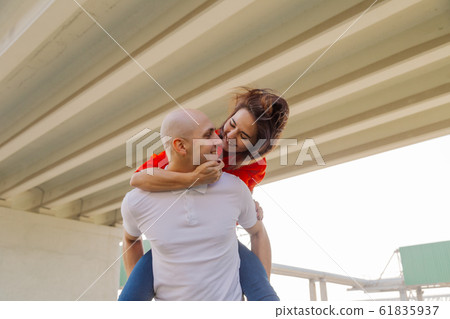Happy girl on the back of a man at the bridge Happy girl on the back of a man at the bridge 61835937