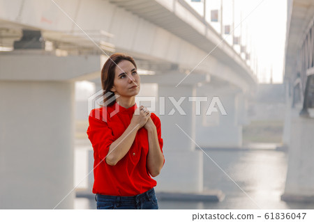 Beautiful girl stands at the bridge near the river 61836047