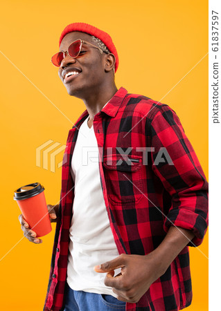 portrait of a black american man dressed stylishly holding a drink glass on a coffee break yellow 61837597