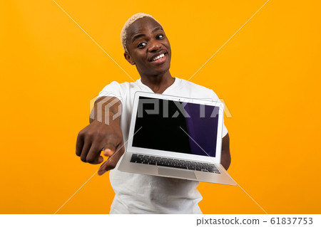 smiling cute american in white t-shirt showing laptop display with mockup and pointing finger 61837753