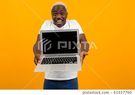 attractive joyful surprised american man in white t-shirt holds out his hands with laptop with 61837760